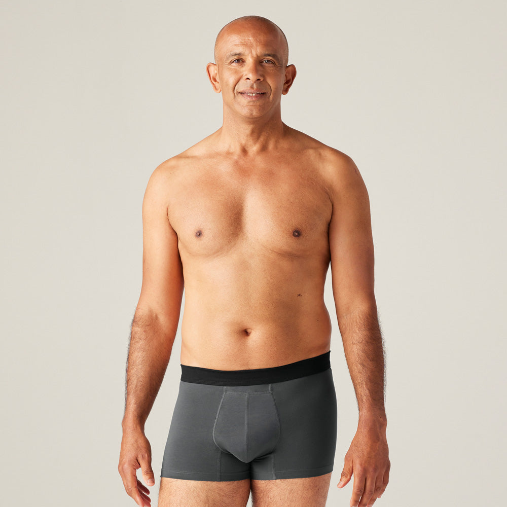 Un homme portant un boxer absorbant lavable TENA, conçu pour l'incontinence légère, apparence classique et confortable, invisible sous les vêtements.