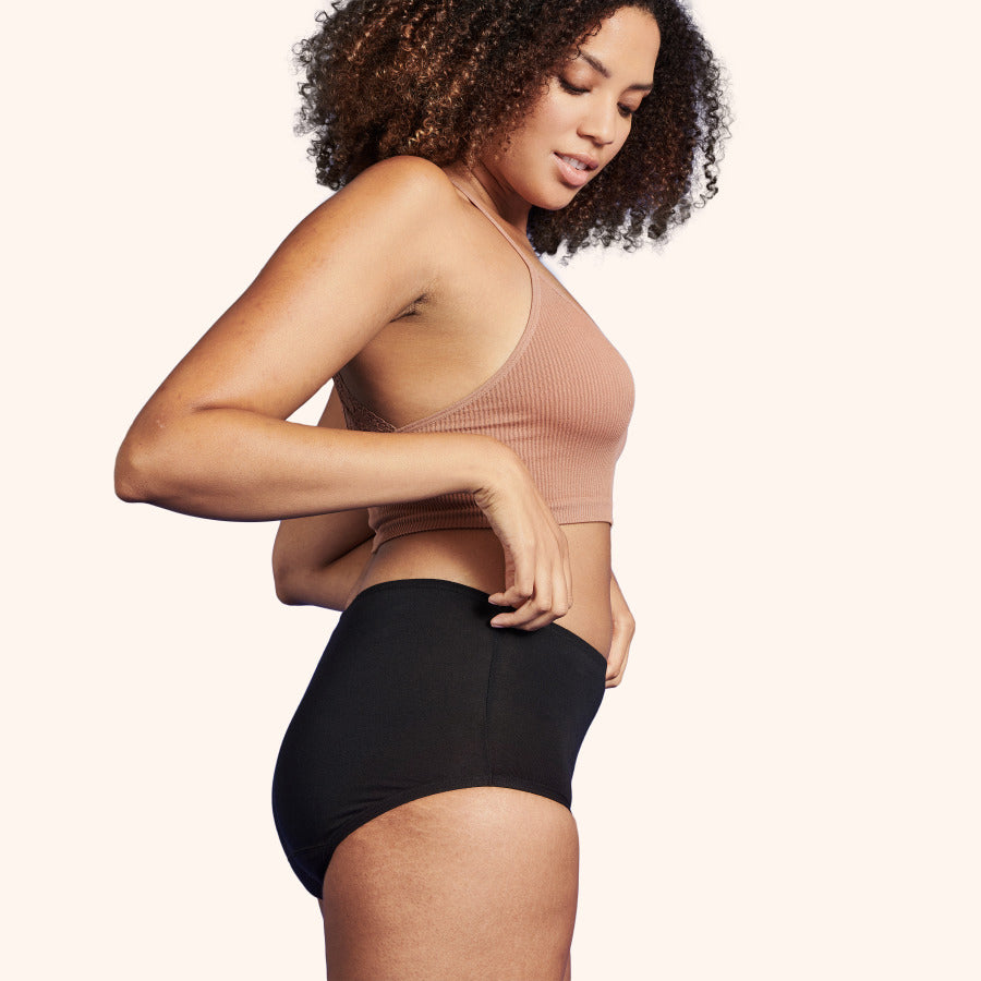 Gros plan d'une femme portant la TENA Culotte Absorbante Lavable en Coton Doux | Taille Classique, mettant en valeur sa coupe haute et bande taille confortable.