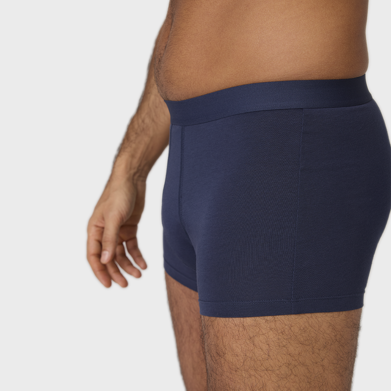 Homme portant le Nouveau Boxer absorbant lavable homme, conçu pour l'incontinence légère, avec ceinture élastique anti-roulement, aspect classique et confort en coton biologique.
