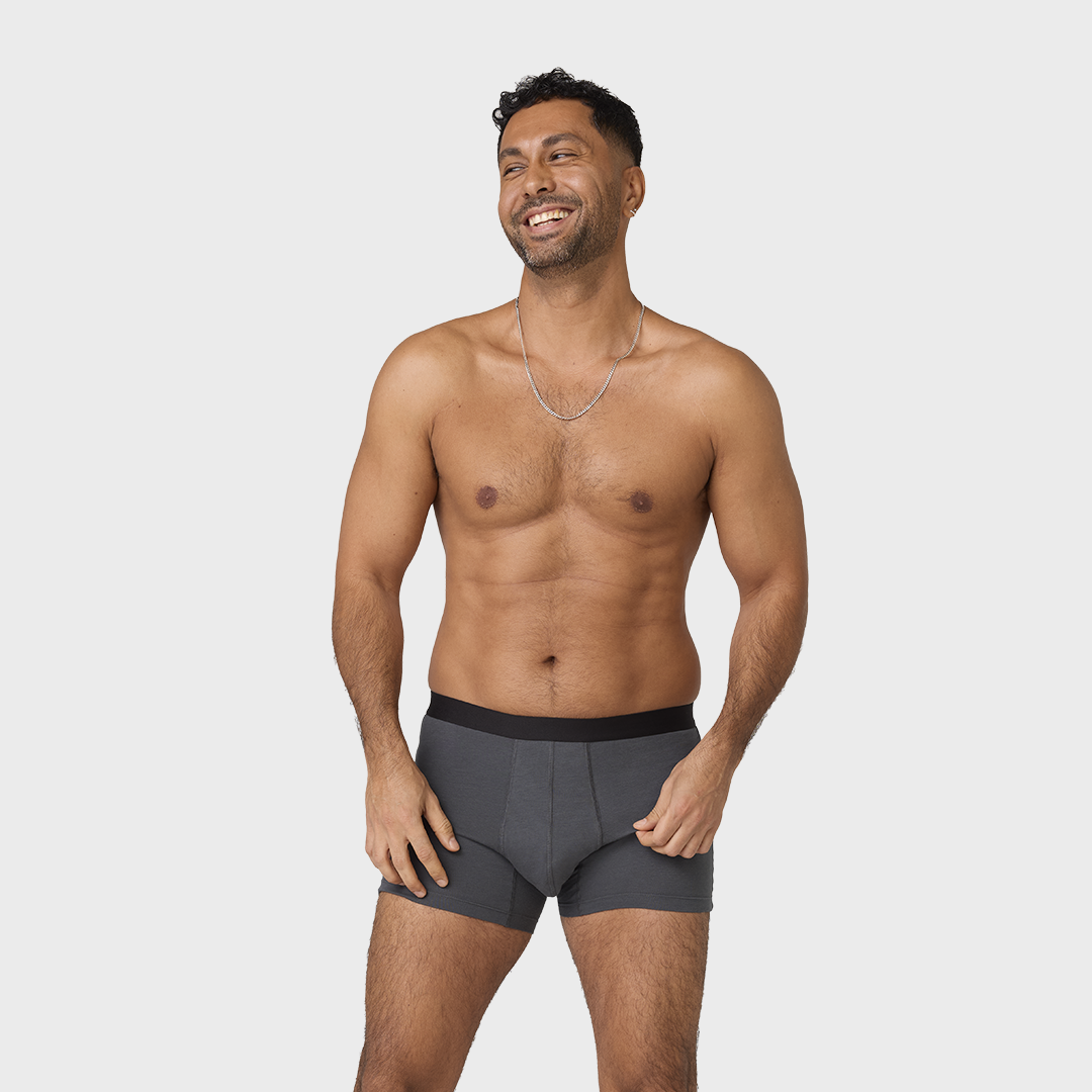 Homme souriant portant le Nouveau Boxer absorbant lavable homme, boxers en coton biologique avec ceinture noire, offrant confort et protection pour incontinence légère.